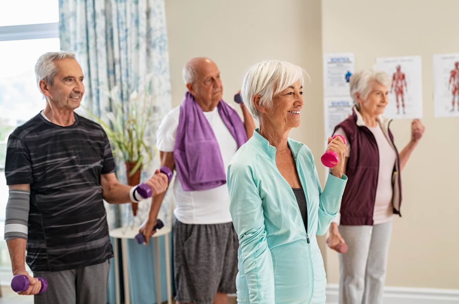 A group of smiling older adults enjoying a fitness class in a retirement community.
