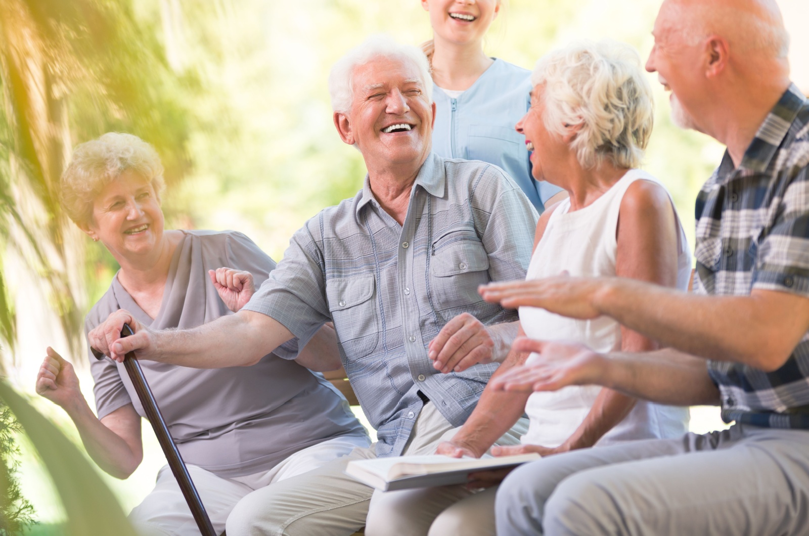 A group of happy older adults from a retirement community socializing outdoors.