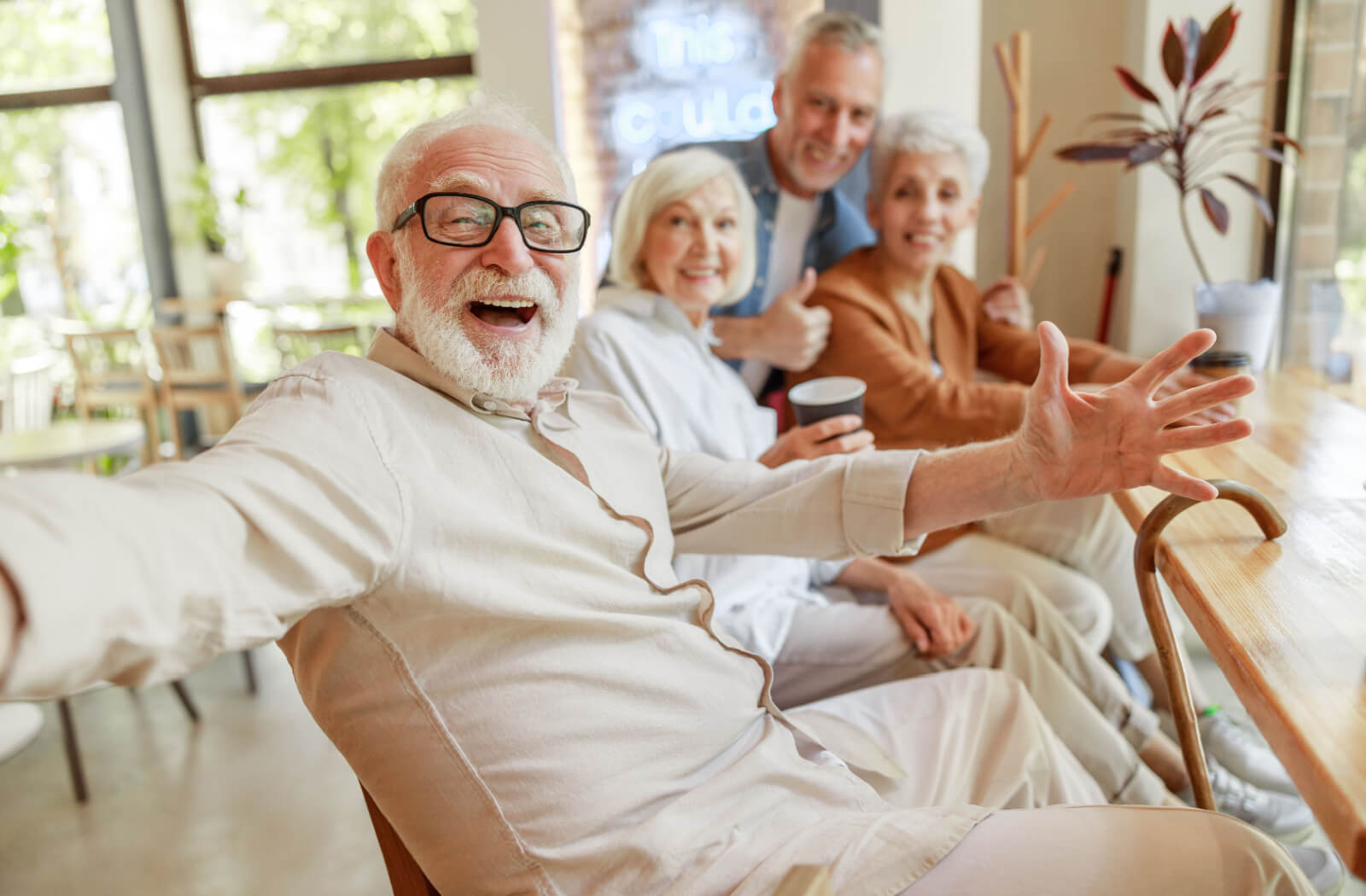 A group of 4 older adults sit in a row and laugh during a group activity in senior living