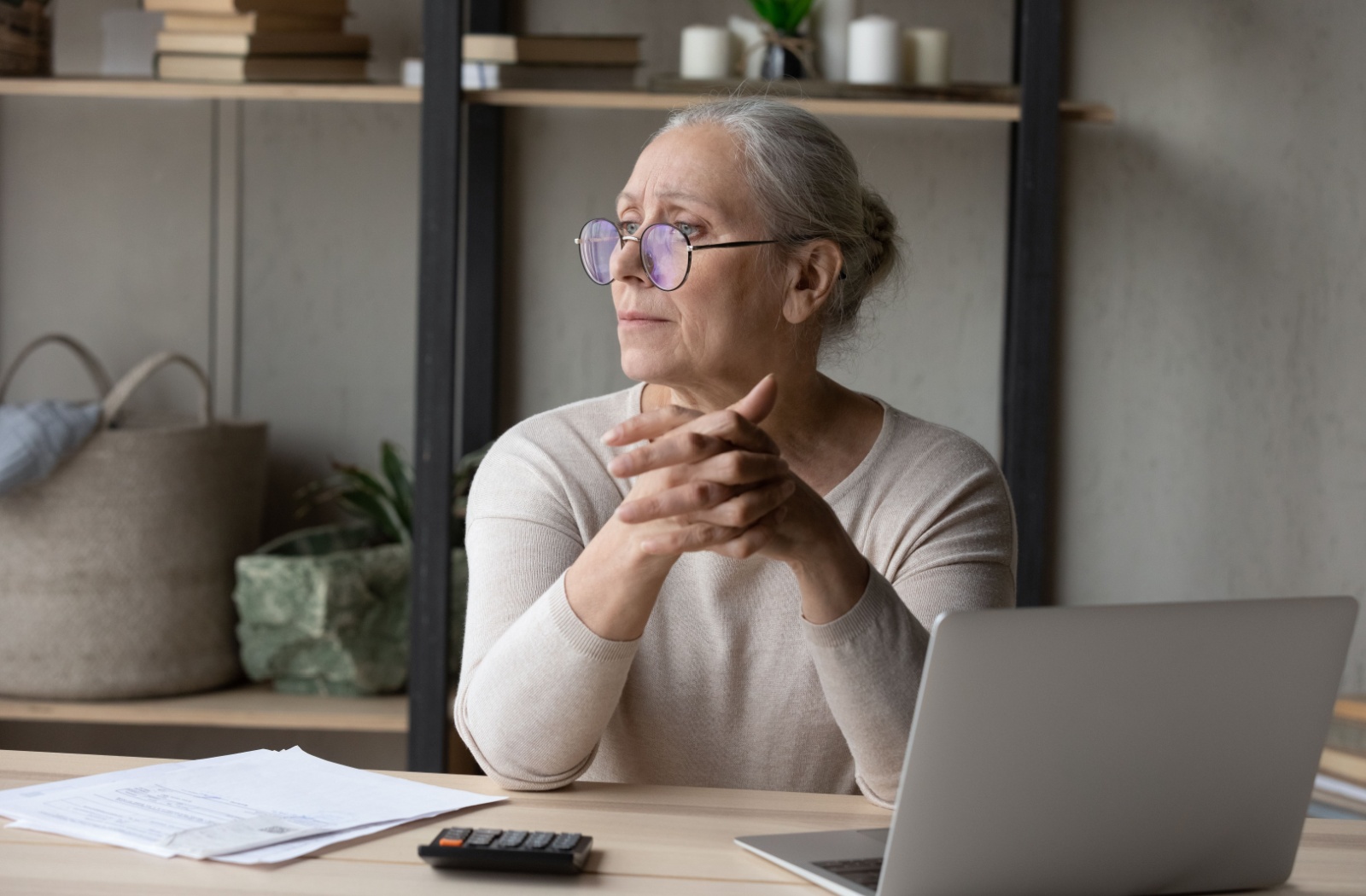An overwhelmed senior dealing with paperwork takes a moment to stare off into the distance, consumed by stress