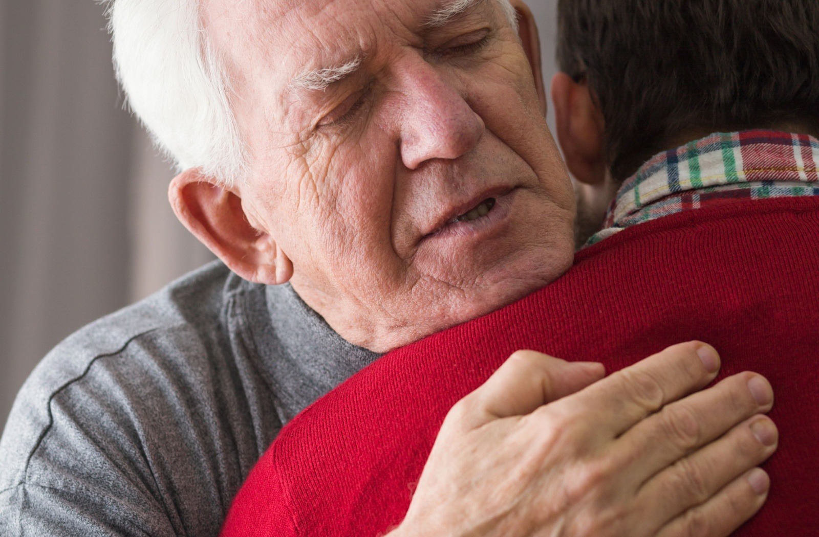 Close-up of a senior with dementia embracing their adult child.